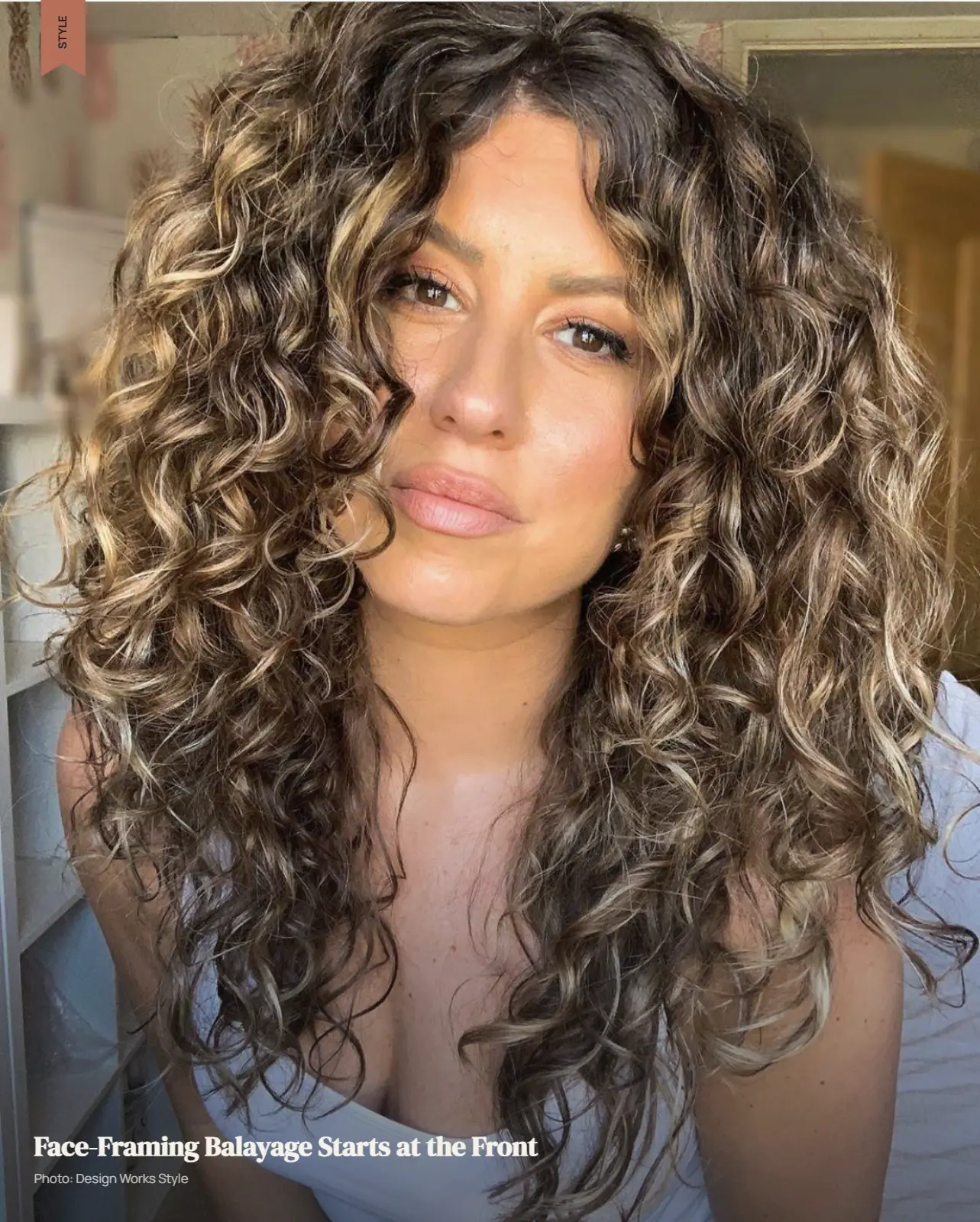 Curly hair with lighter balayage pieces concentrated around the face