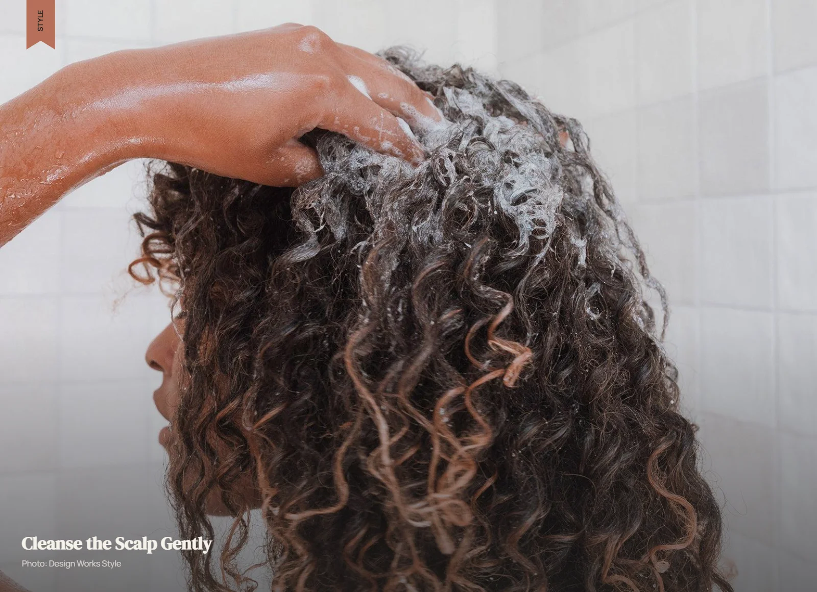 Hands gently cleansing the scalp of curly hair with shampoo
