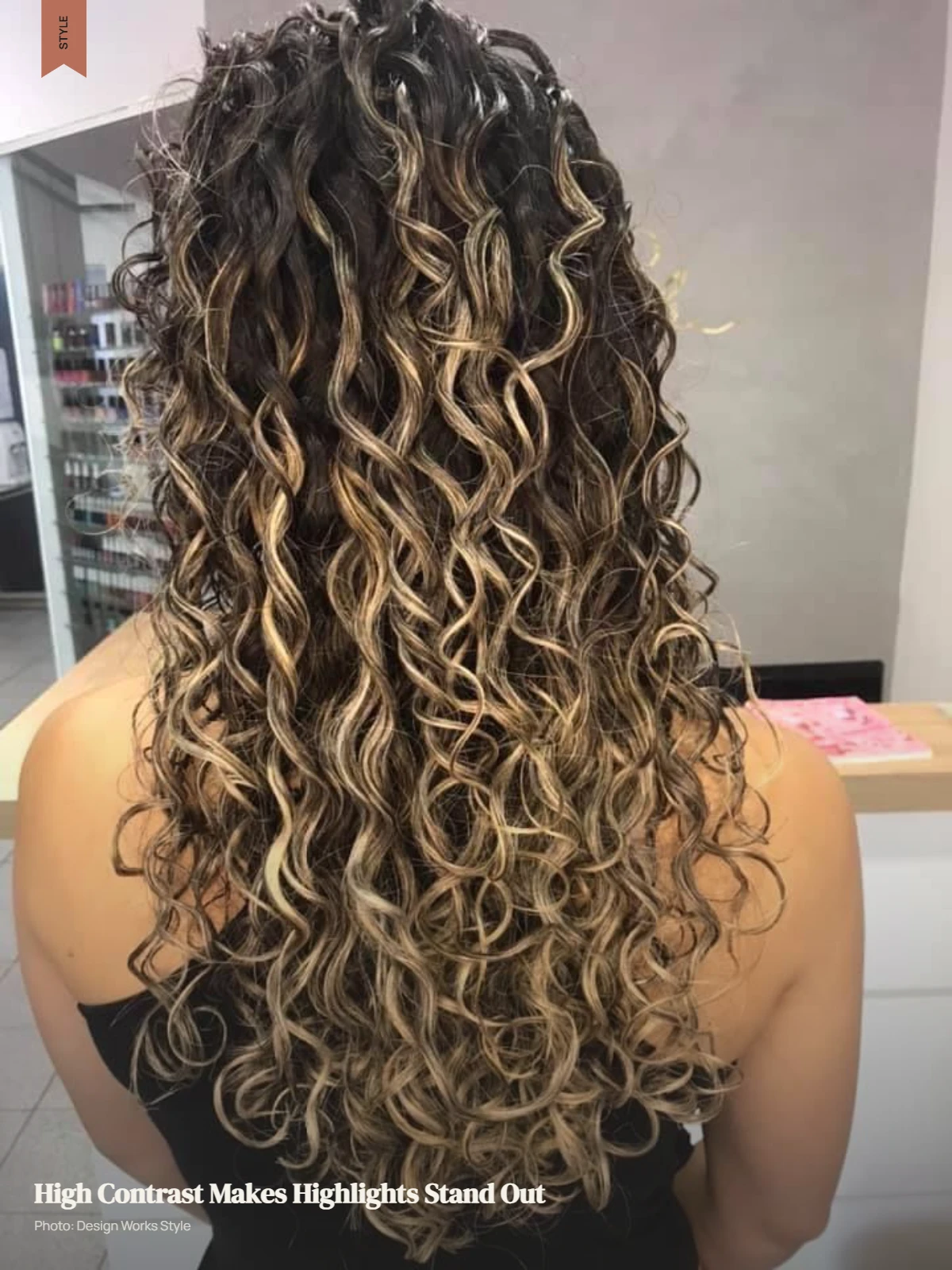 Curly dark hair with bright balayage pieces creating strong contrast across the curls