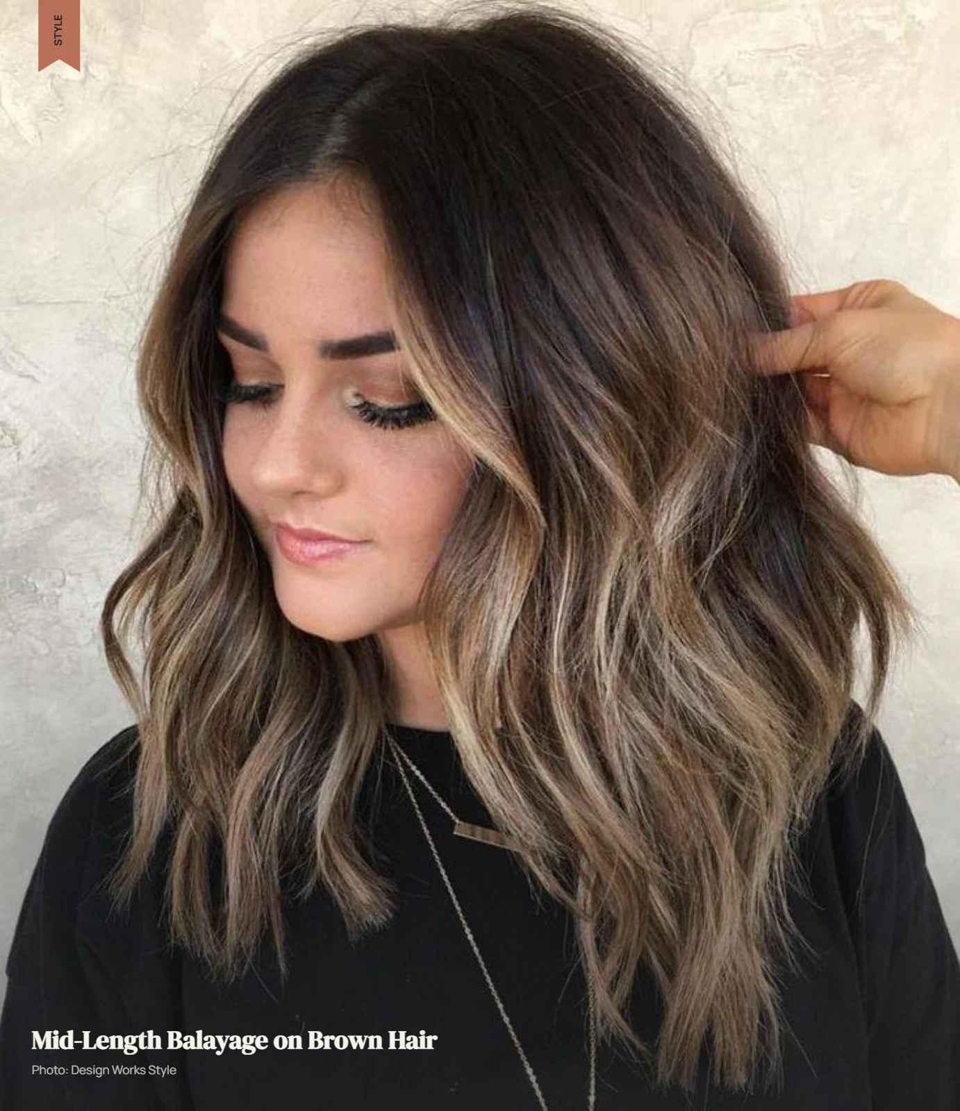 Brown hair with balayage placed through the mid-lengths while darker roots remain visible