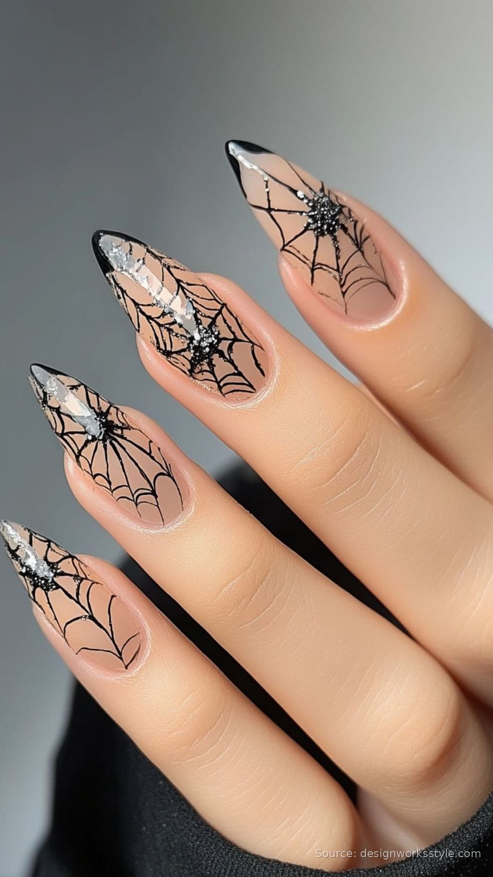 Black spiderweb nail art on nude almond nails with glitter spider accents