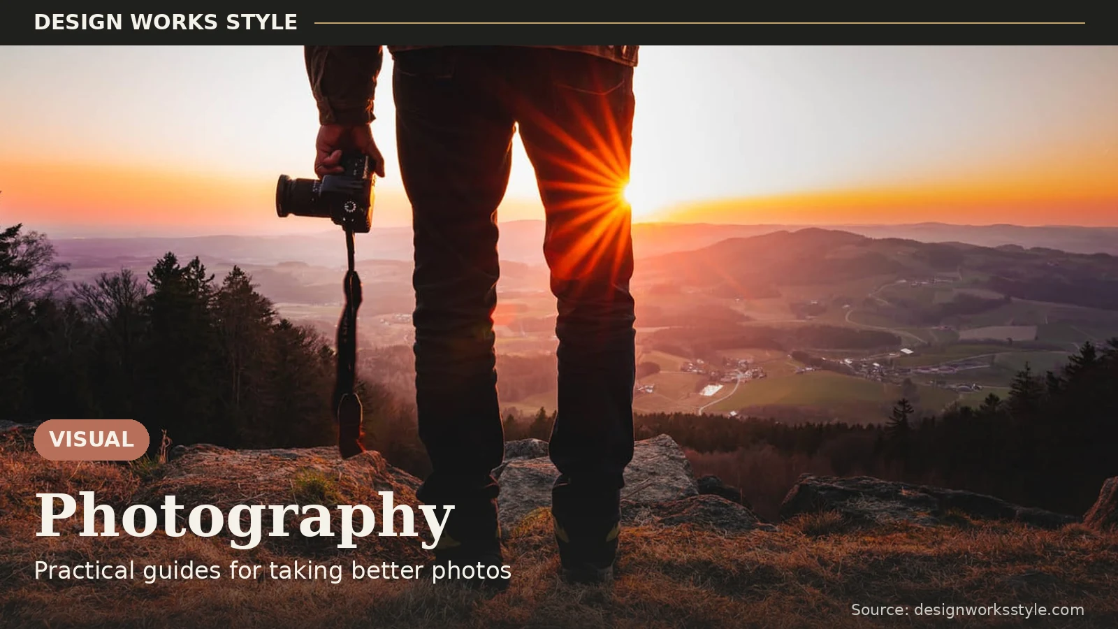 Photographer holding a camera looking at a sunrise over mountains