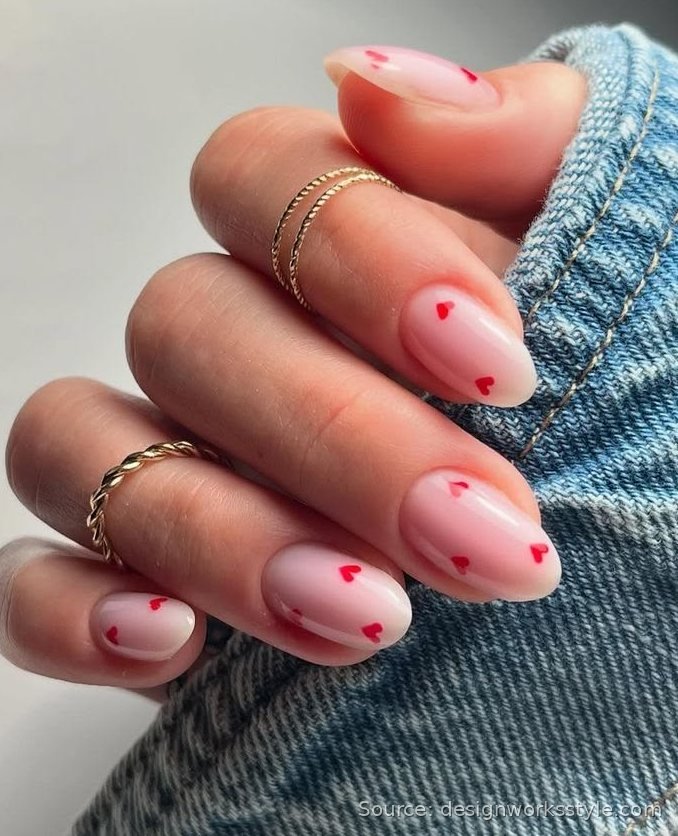Tiny red heart accent nail art on sheer pink nails